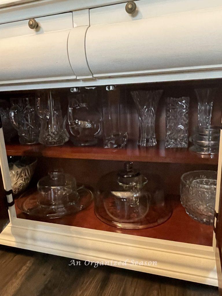 Glass serving dishes stored in the bottom of a china cabinet showing how to organize your dining room for easy entertaining. 