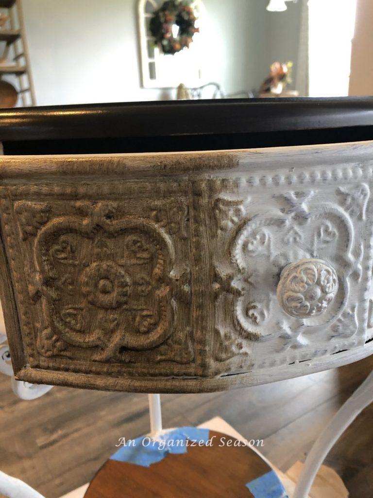 Brown wax applied over white paint on a living room end table, showing final step of furniture makeover.