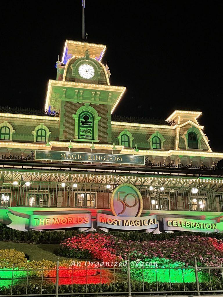 The entrance to Magic Kingdom lit with red and green lights welcoming guests to Disney's Very Merriest After Hours party we wrote a guide for.