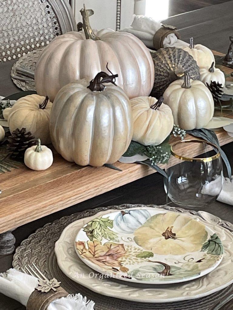 A dining room table decorated with pumpkins that match the plates of the table setting. The second room in the best of Autumn home tour.
