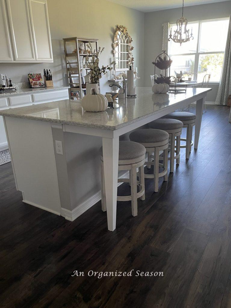A kitchen island decorated with pumpkins and pinecones, showing the fourth room in the best of Autumn home tour.