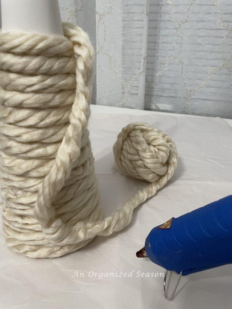 Yarn being wrapped around a cone and attached with hot glue.