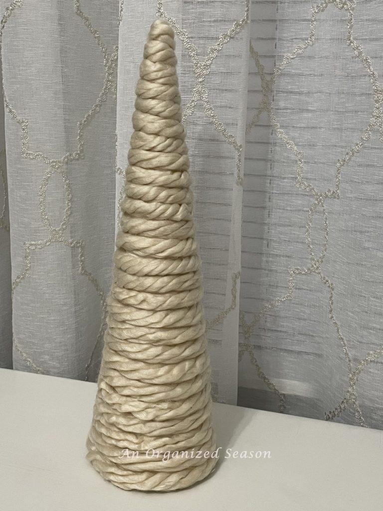 A cone covered with tan chunky yarn. A finished example of a DIY cone Christmas tree.