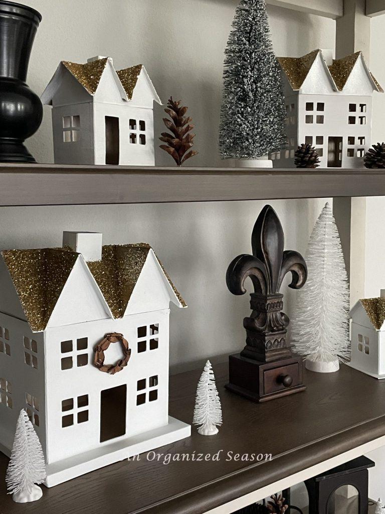 A DIY Christmas village displayed on bookshelves.  