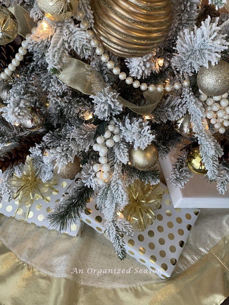 A Christmas tree decorated to match a wreath in gold and white with matching packages underneath.