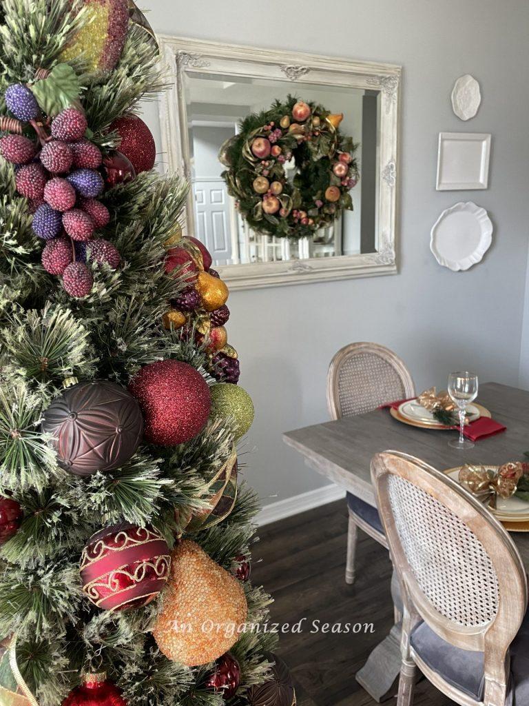 A Christmas wreath hanging on a mirror in a dining room that is covered with fruit. 