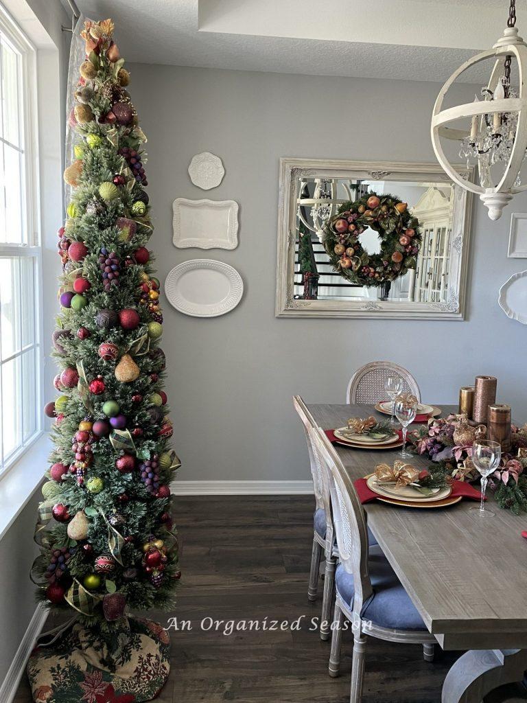 Dining room decorated for Christmas with a tree, wreath and table setting. 