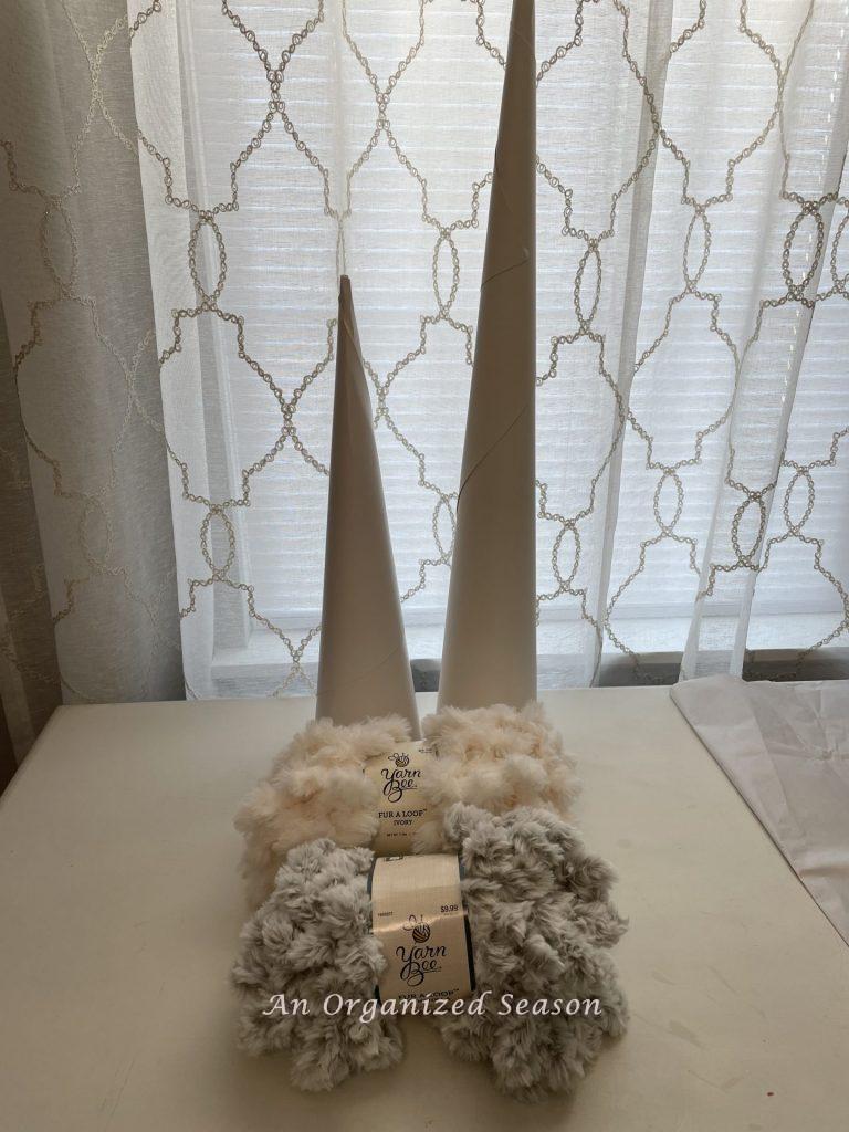Two white cones and two packages of faux fur yarn.
