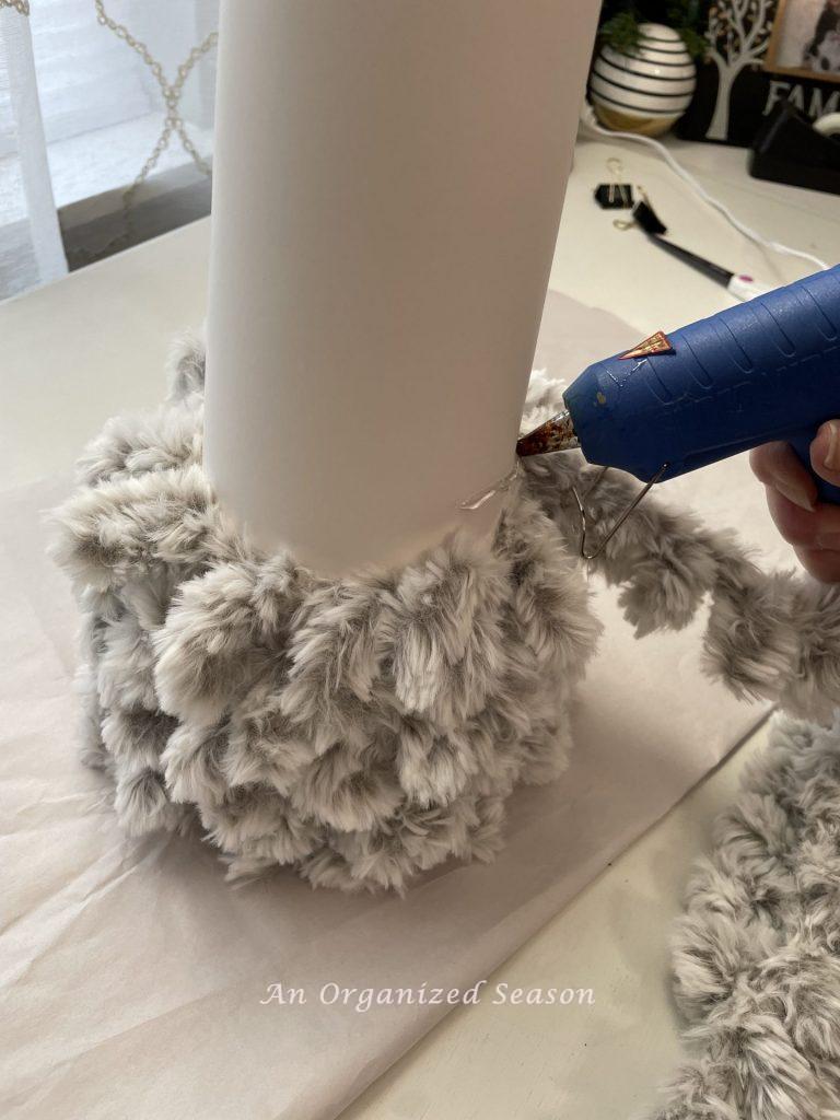 Faux looped fur being glued onto a cons showing how to make a DIY cone Christmas tree.