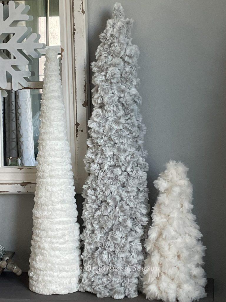 Three yarn cone Christmas Trees sitting on a shelf.