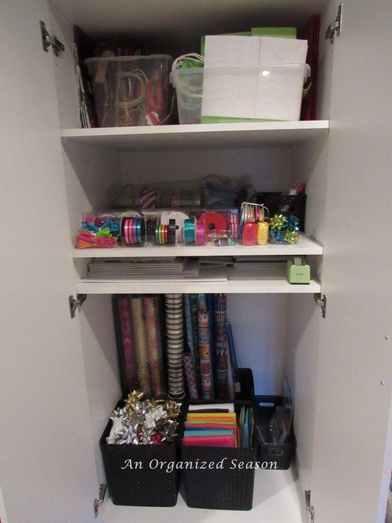 A cabinet set up as an organized gift wrapping station. 