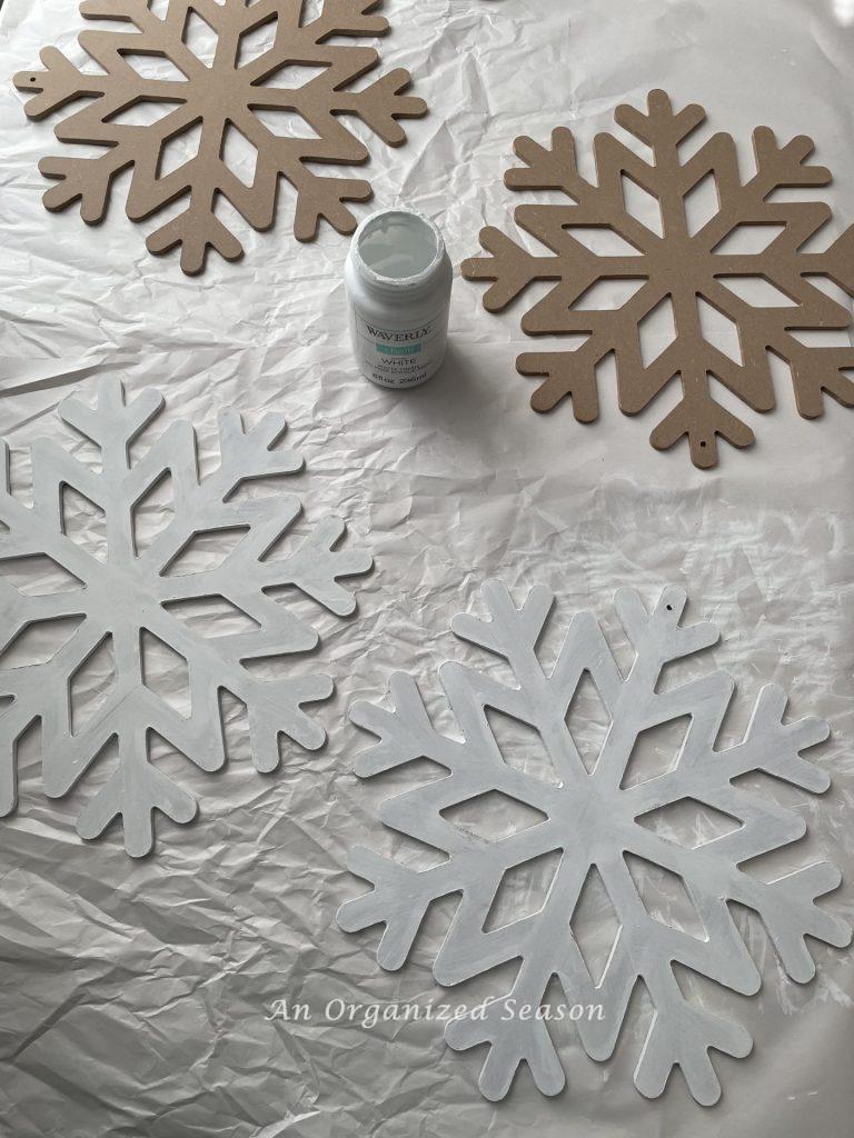 Four snowflakes with two of them painted white. Step three for how to make a cheap but cute tree topper.