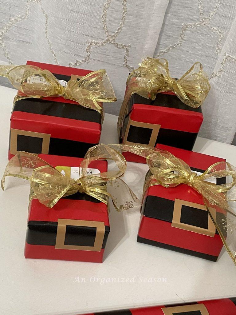 Four Christmas gifts wrapped in Santa Claus belt paper. 