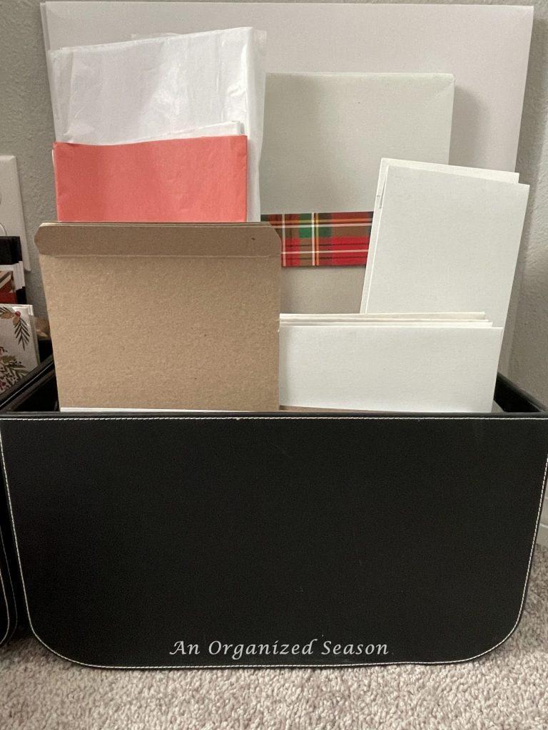 Gift boxes and tissue paper organized in a black box that are part of my Christmas gift wrapping station.