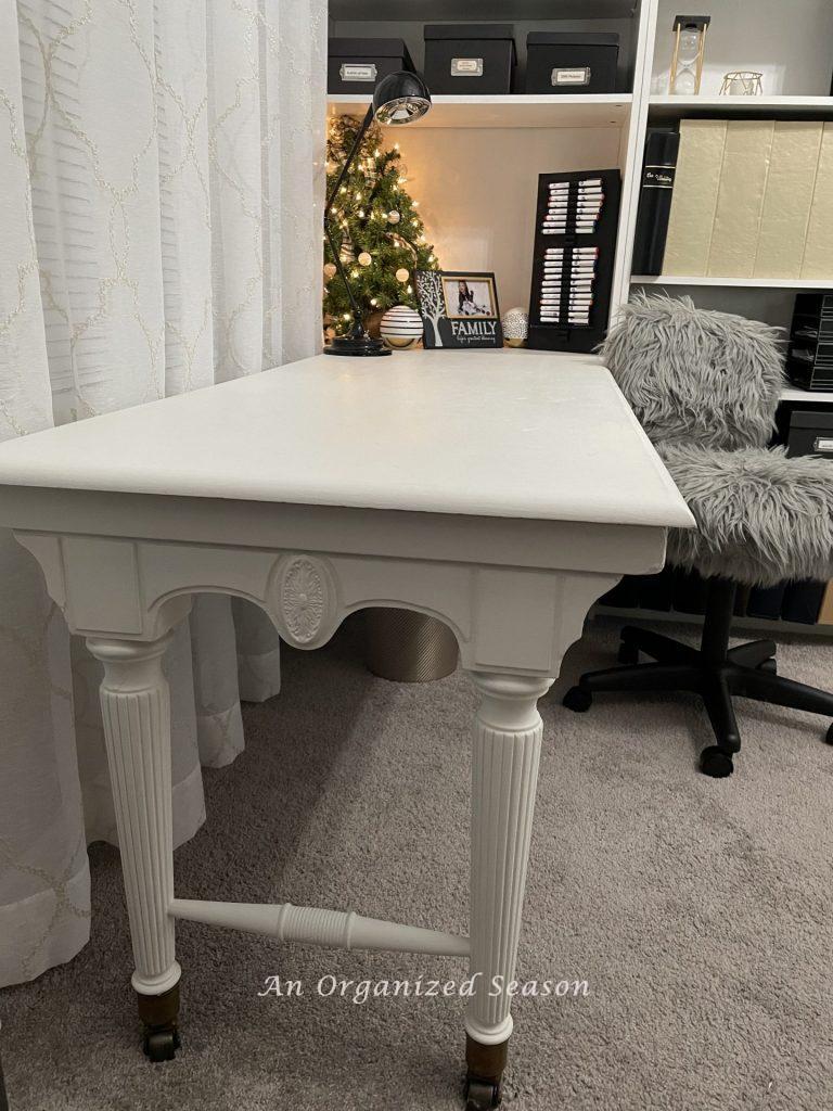 A white desk, next to bookshelves that could be used as a Christmas gift wrapping station.