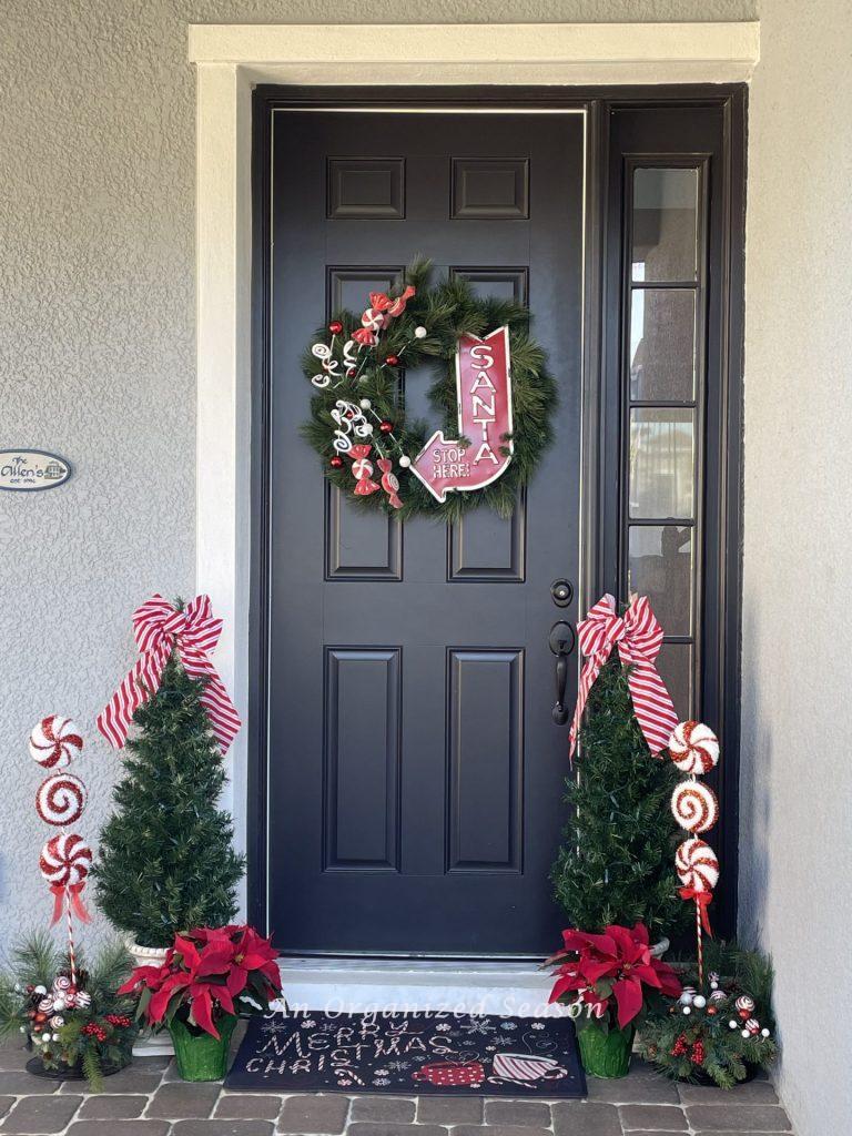 A front door decorated for Christmas with red and white. 