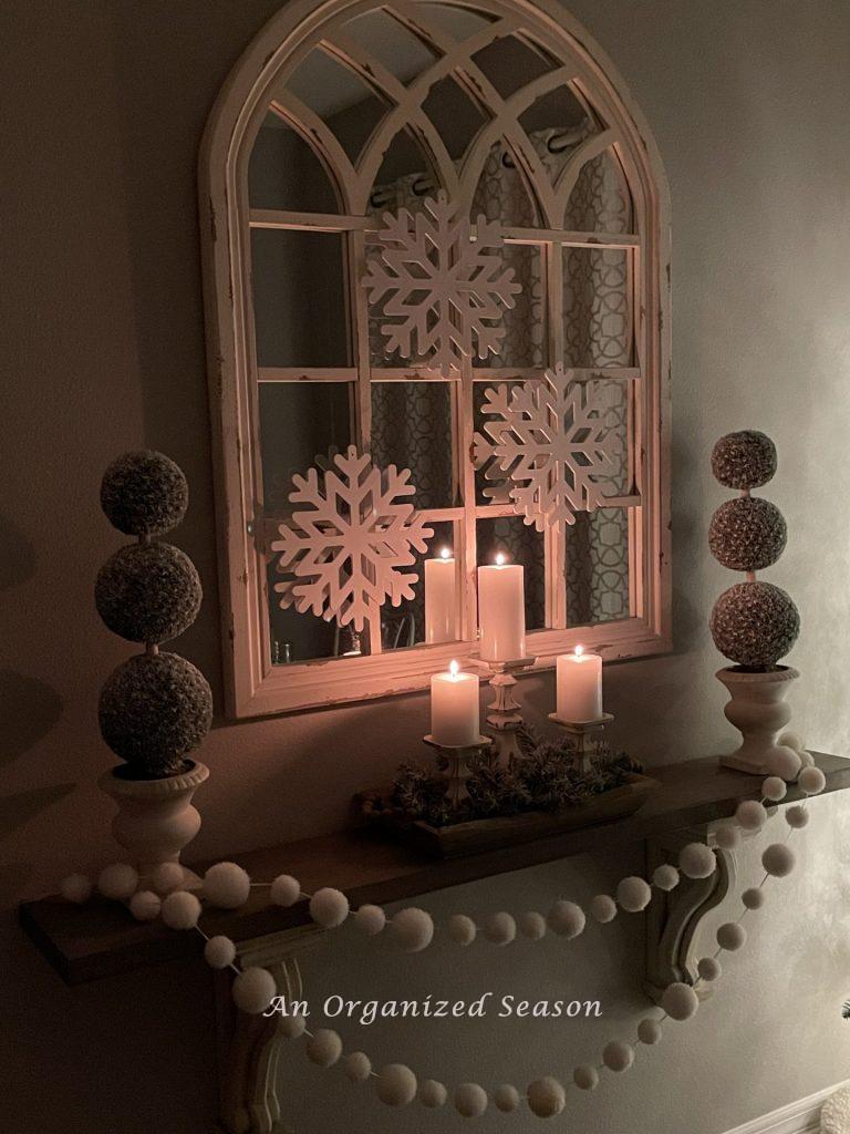 Three white candles twinkling on a shelf during the Tis the season nighttime home tour.