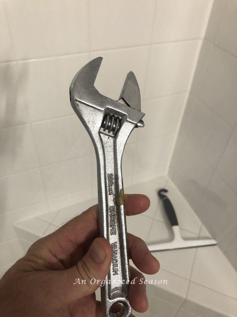 A man holding a wrench used to easily install a new shower head.