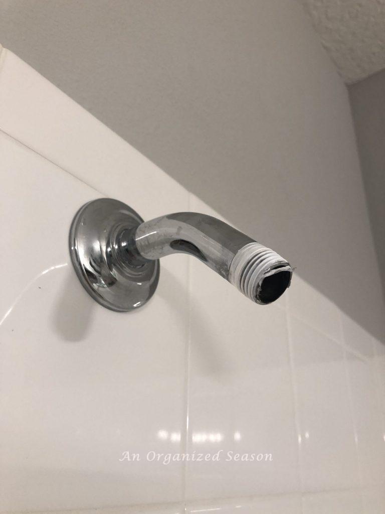 A shower pipe with old plumbers tape that needs to be removed before easily installing a new shower head.