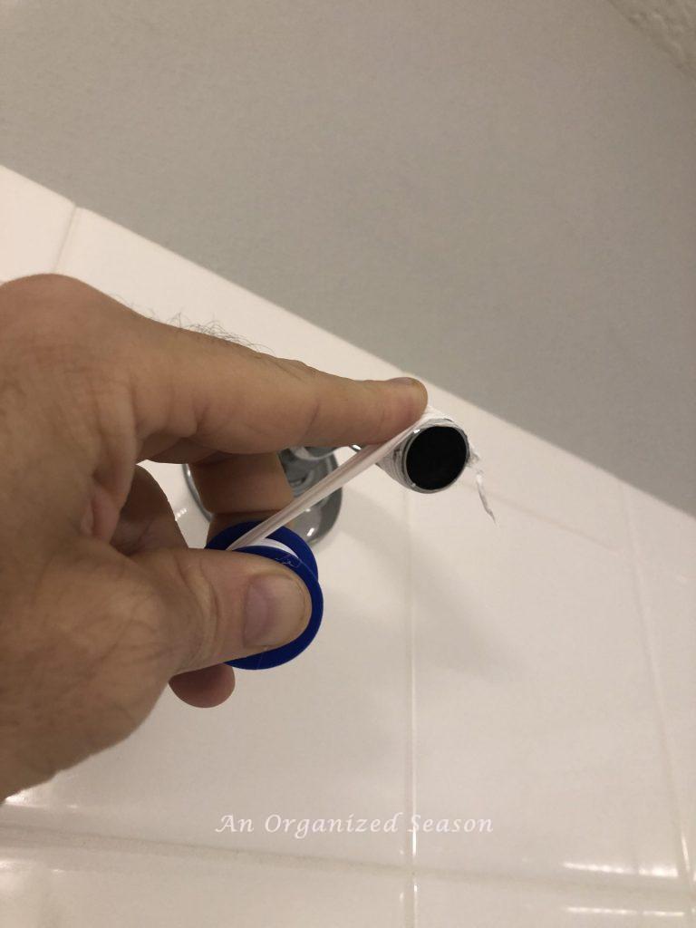 A man putting plumbers tape on a shower pipe to easily install a new shower head.