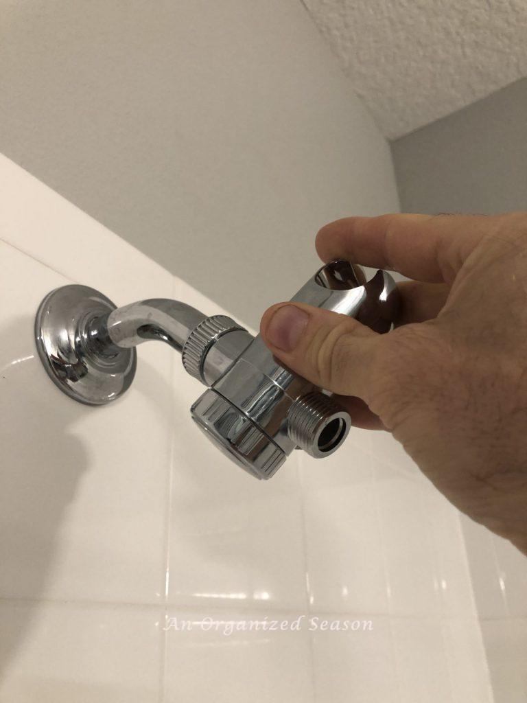 A man screwing a valve onto a shower pipe showing a step to easily install a new shower head.