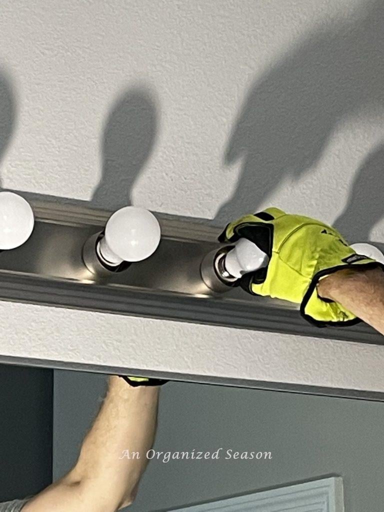 Removing old light bulbs is step one to replace a bathroom light fixture.