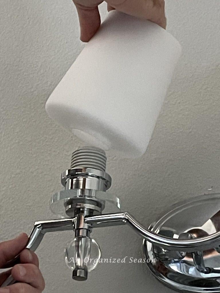 Last step to replace a bathroom light fixture is to screw the shade onto the fixture.
