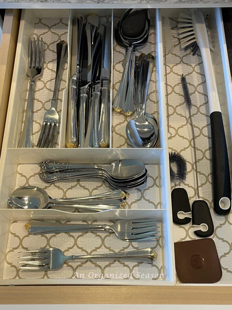 A utensil tray with divided sections showing how to organize knives, forks, and spoons in a kitchen drawer.
