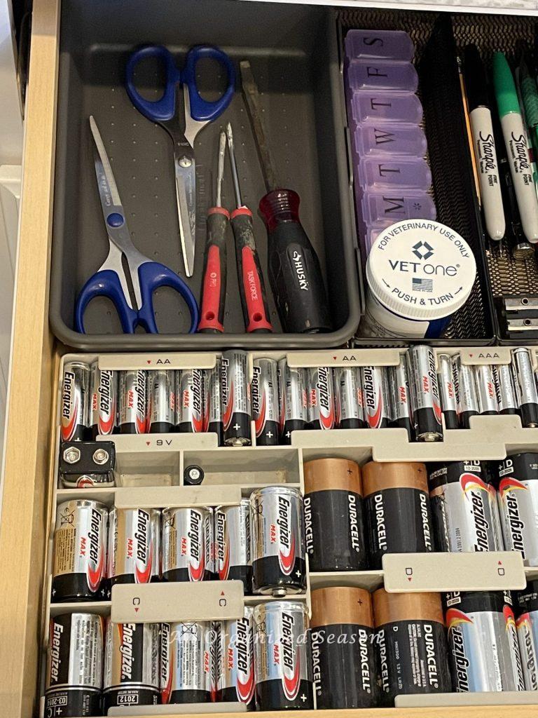 A kitchen junk drawer showing how to organize batteries, scissors, tools, and meds. 
