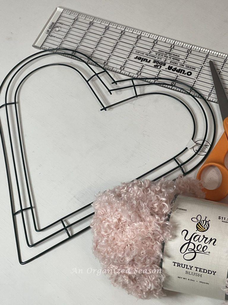 Heart shaped form, Teddy Bear Yarn, scissors and a ruler used to craft a Valentine's Wreath.