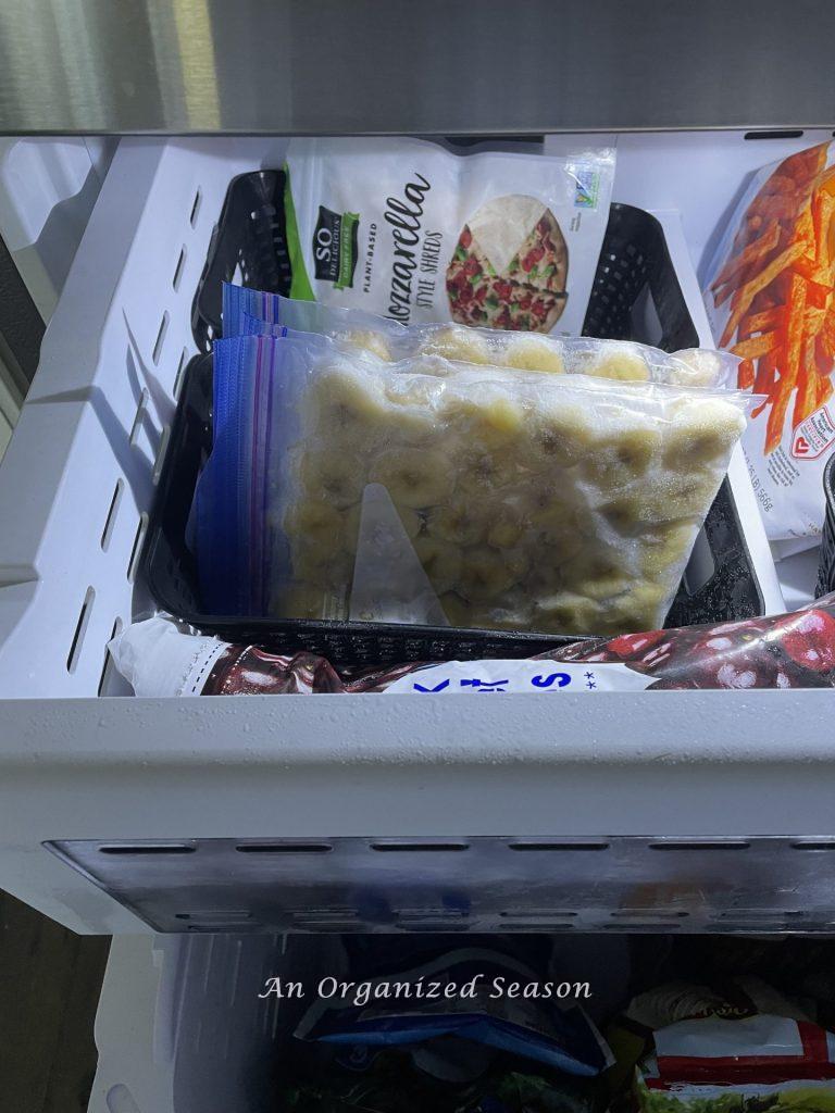 Frozen bags of fruit and cheese that are stored in plastic baskets to organize a freezer. 