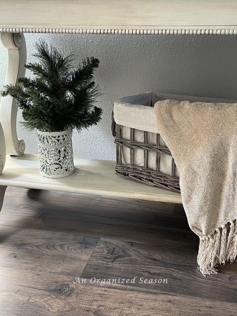 A basket with a throw blanket draped over it to decorate a home for Winter. 