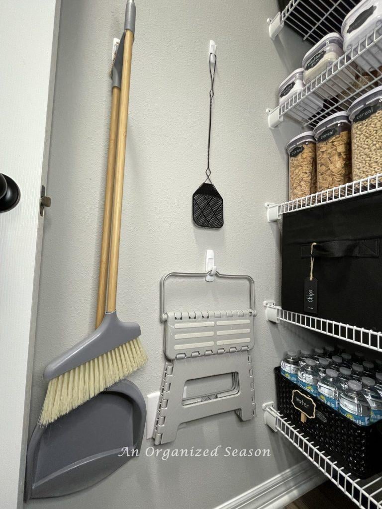 A clever tip to organize your pantry is to use command hooks to hang items on the wall.