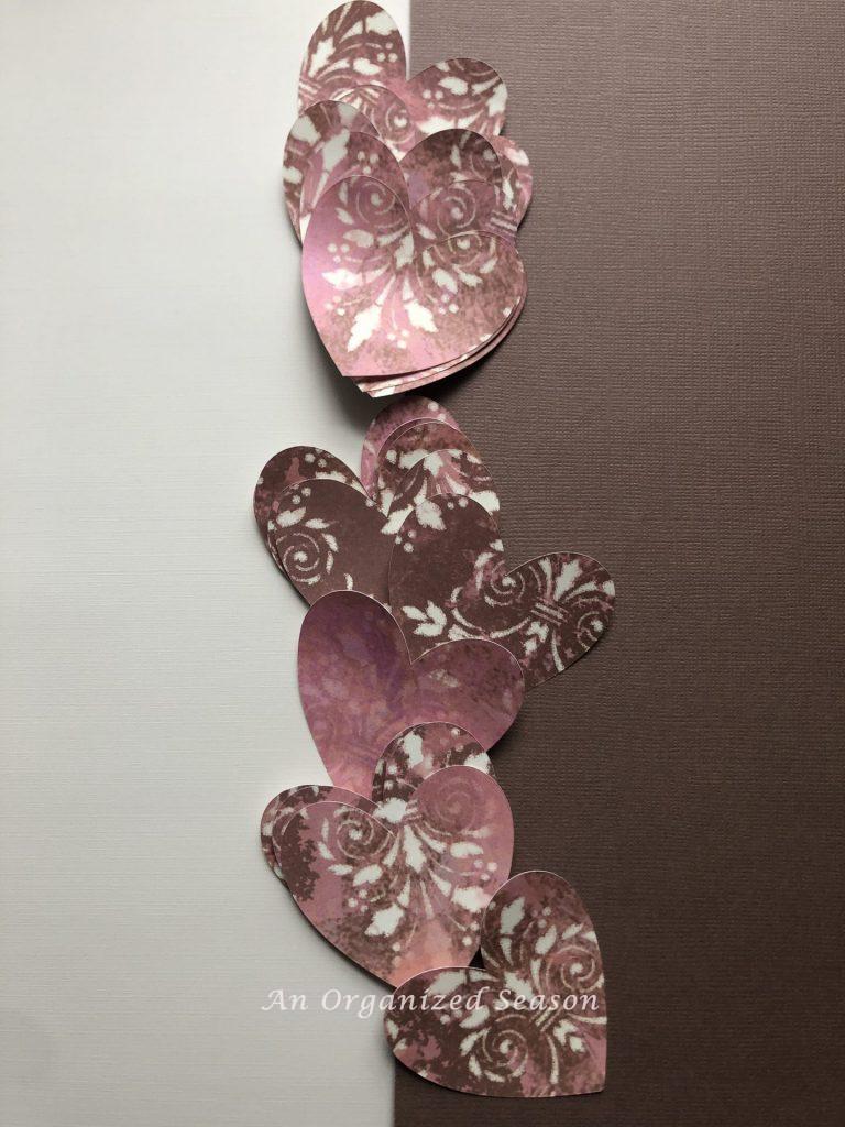 Hearts cut out of pink, brown and cream colored cardstock for a paper heart and ribbon garland.