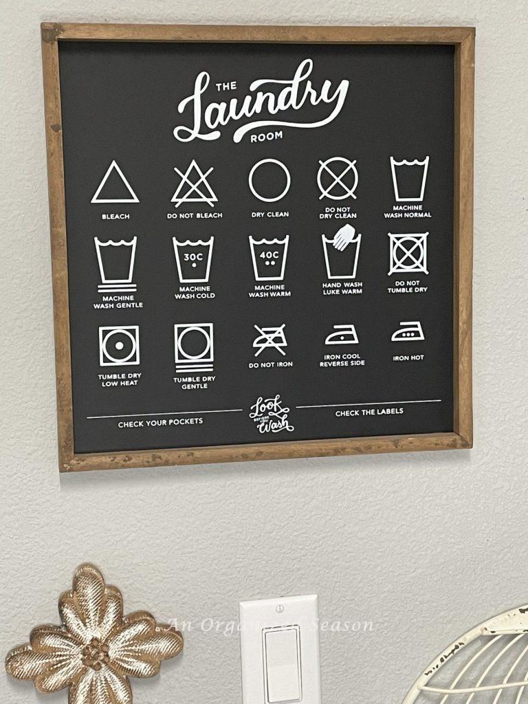 A chalkboard sign hanging in a laundry room with the symbols for washing clothes. Showing how to simplify the chore of laundry.