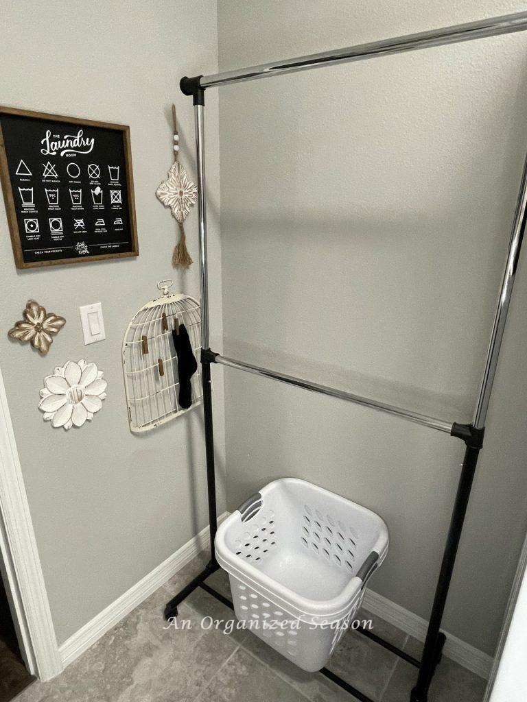A clothes hanging rack in a laundry room is an example of practical laundry room organization ideas.