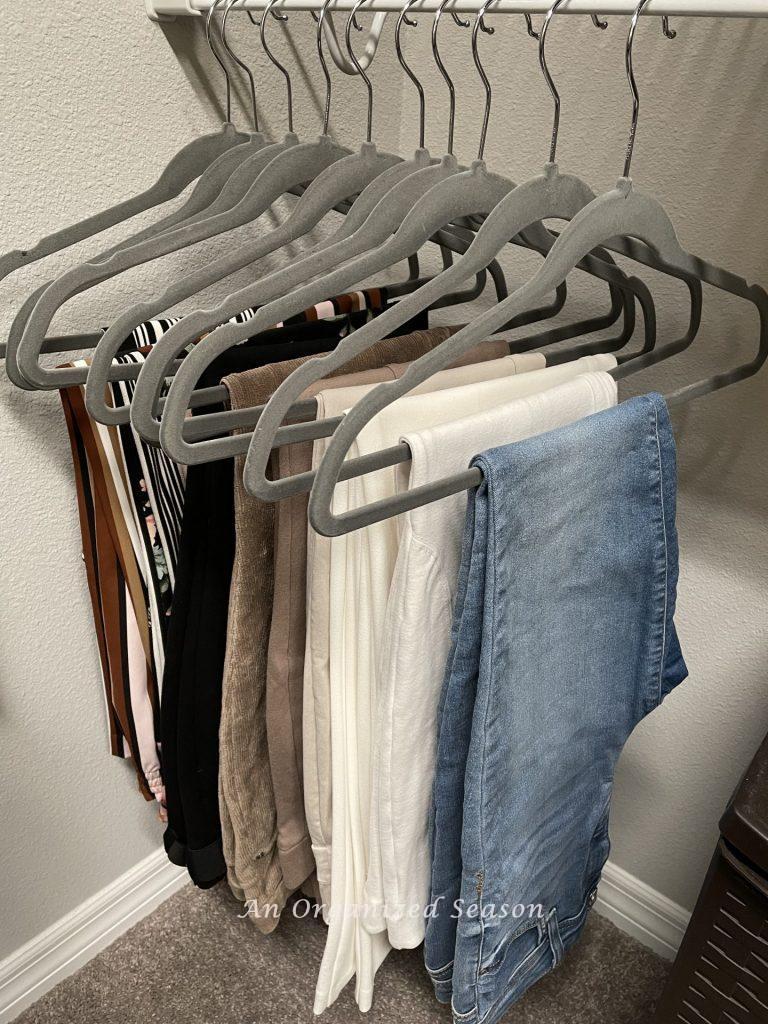 Pants hanging in an organized closet showing how to simplify the chore of laundry.