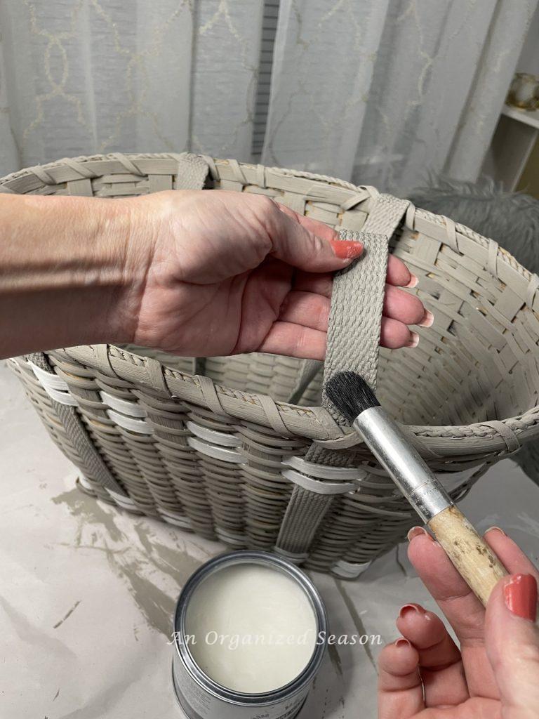 A woman putting wax on the straps of a basket, step three to make a floral basket wreath.