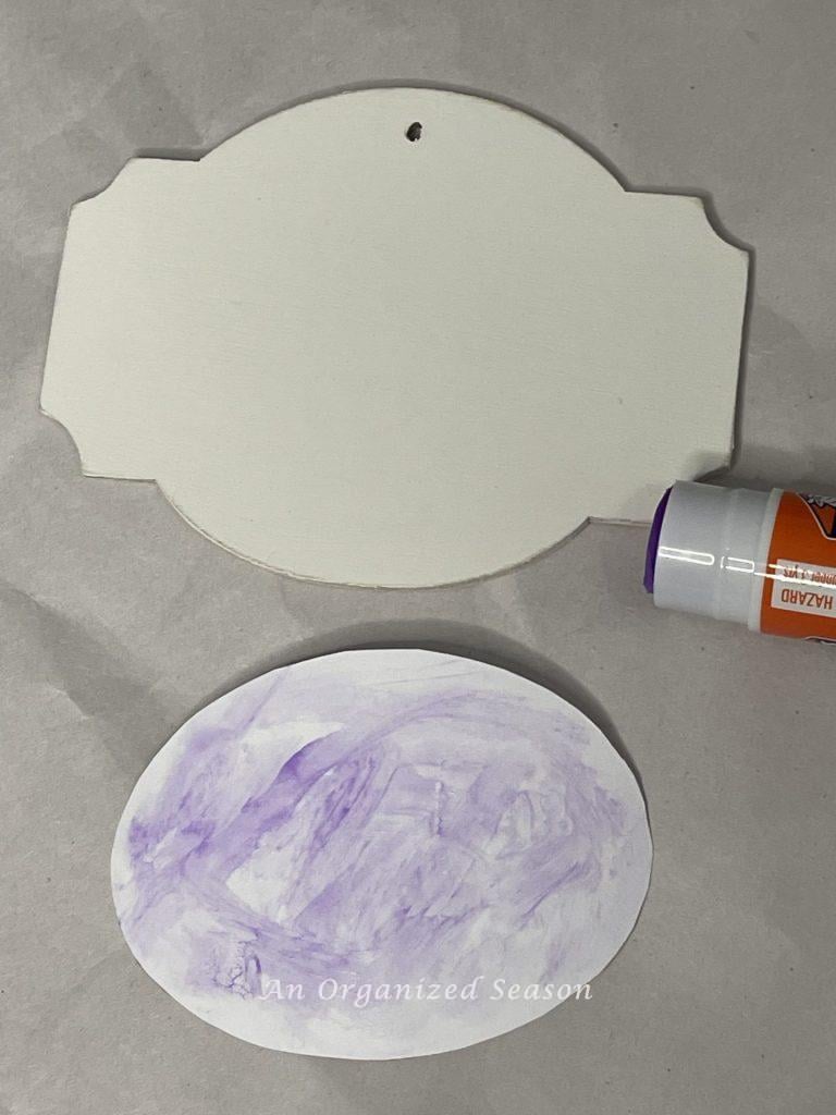 Gluing a label on a wood ta, step four to make a floral basket wreath.