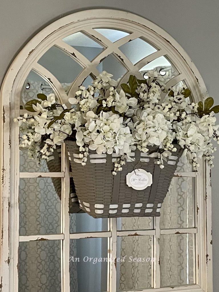 A floral basket wreath hanging on a mirror.