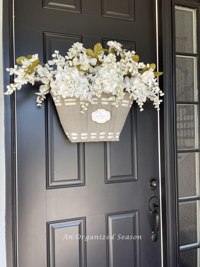 A floral basket wreath hanging on a front door. 
