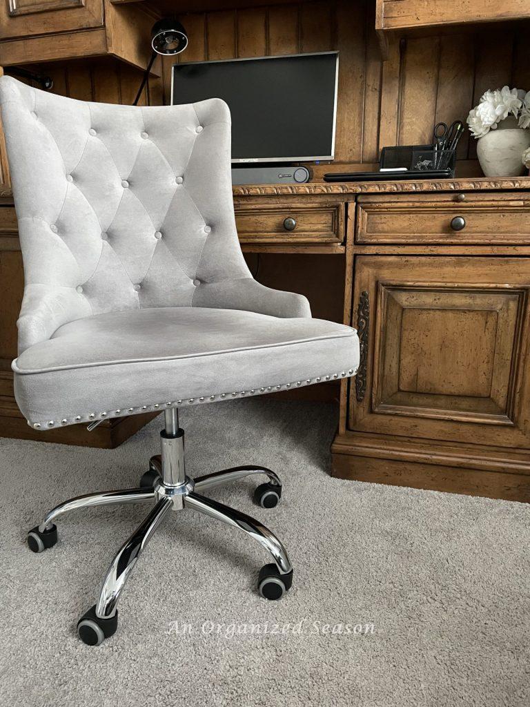 A gray upholstered chair on wheels sitting in front of a desk, an example of Ideas to organize a desk.