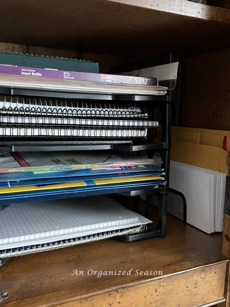 Black plastic stackable trays inside a desk cabinet, an example of ideas to organize a desk.