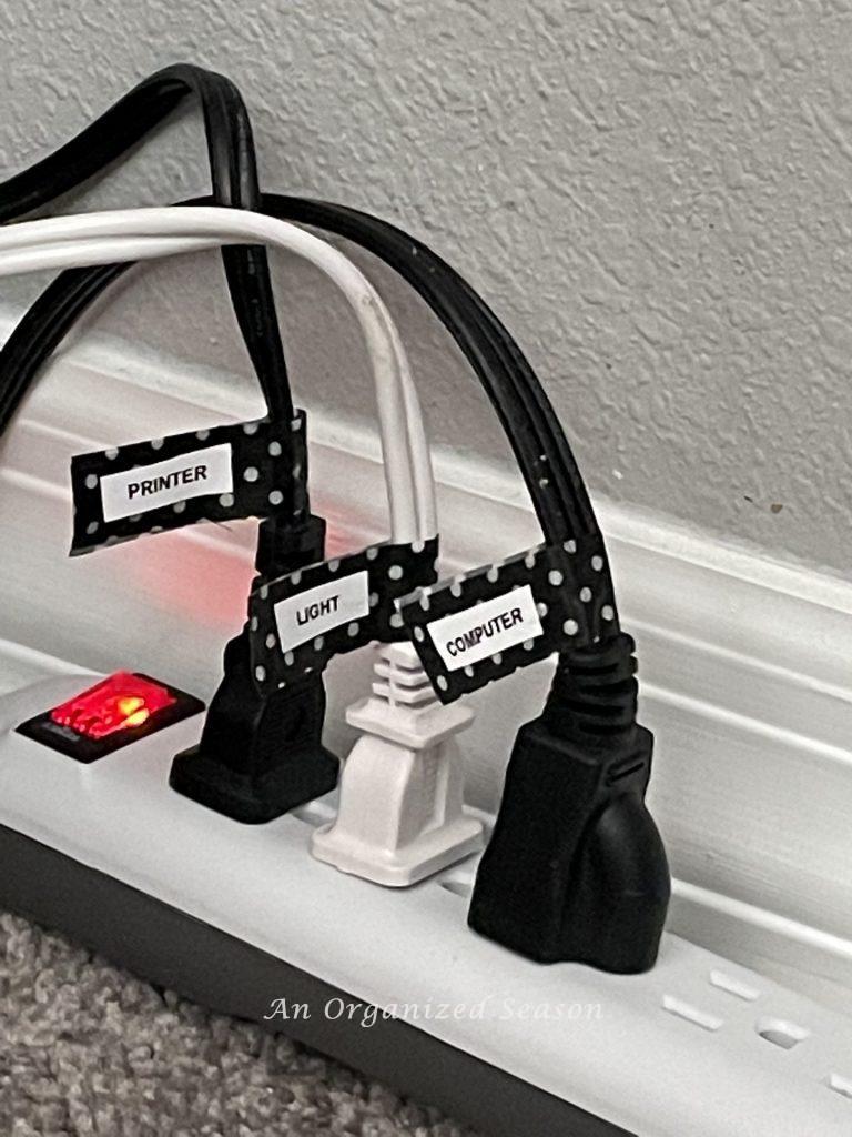 Three cords plugged into an extension cord with tags telling what the cord goes to, an example of ideas to organize a desk.