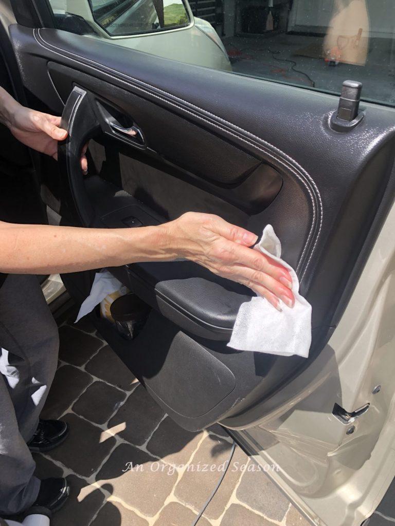 A woman cleaning a car door during the  Spring Home Organization & Improvement Challenge.