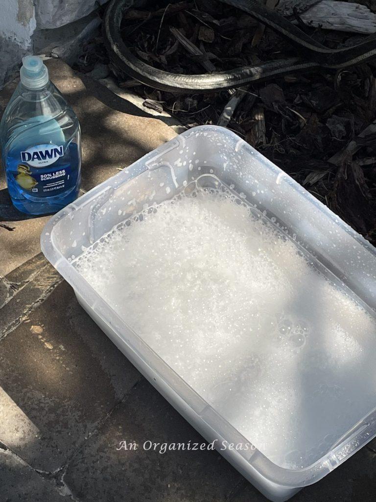 A plastic tub filled with water and Dawn dishwashing liquid to wash a car. Another example of a strategy to clean and organize a car.