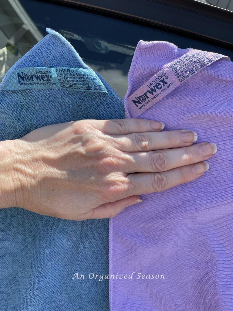 A blue Norwex Enviro Cloth and window cloth to be used to clean car windows, and as a strategy to clean and organize a car.