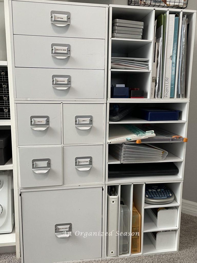 Six white modular cubes used for storing scrapbook supplies, showing ideas to organize a craft space.