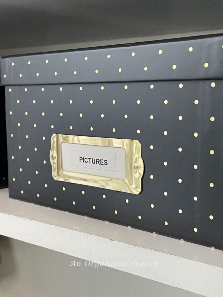 A black photo box with gold dots and a label, showing ideas to organize a craft space.