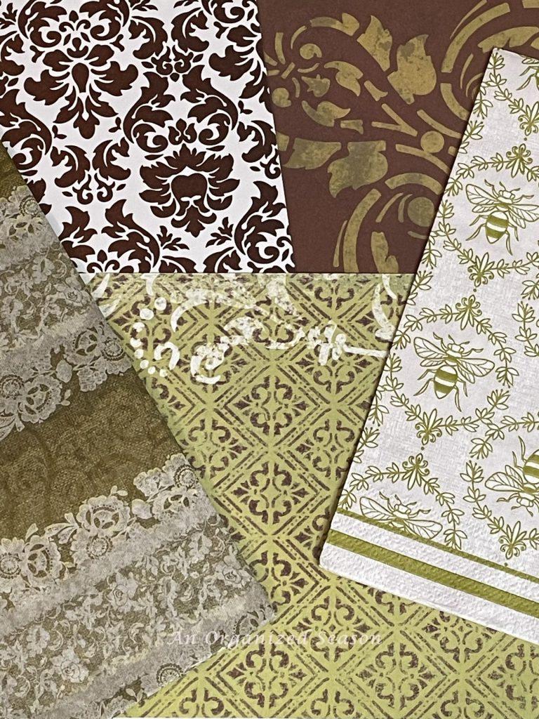Three pieces of scrapbook paper, a napkin, and a piece of tissue paper in coordinating brown and green colors that will be used in a  decoupage Easter egg DIY.